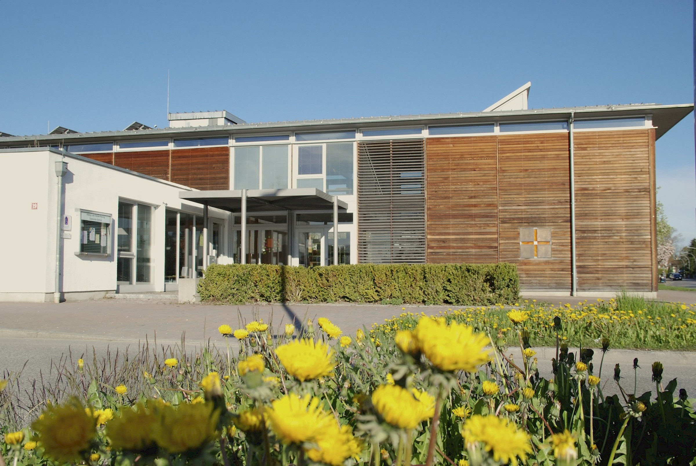 Epiphanias-Zentrum mit Löwenzahn-Blüten im Vordergrund