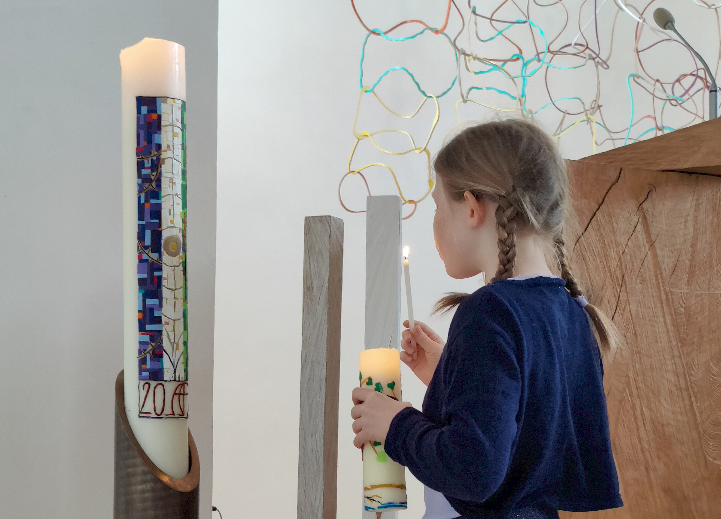 Mädchen zündet die Kindergottesdienst-Kerze an der Osterkerze an